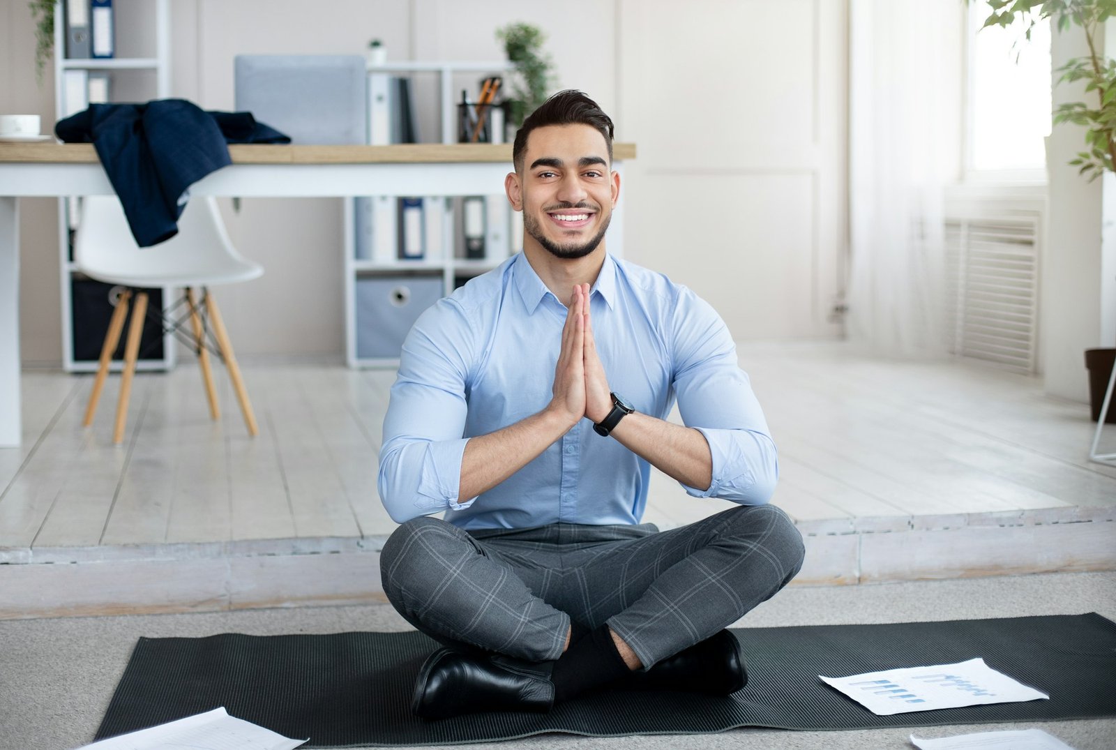 Workplace stress management. Peaceful Arab employee meditating, making namaste gesture on yoga mat